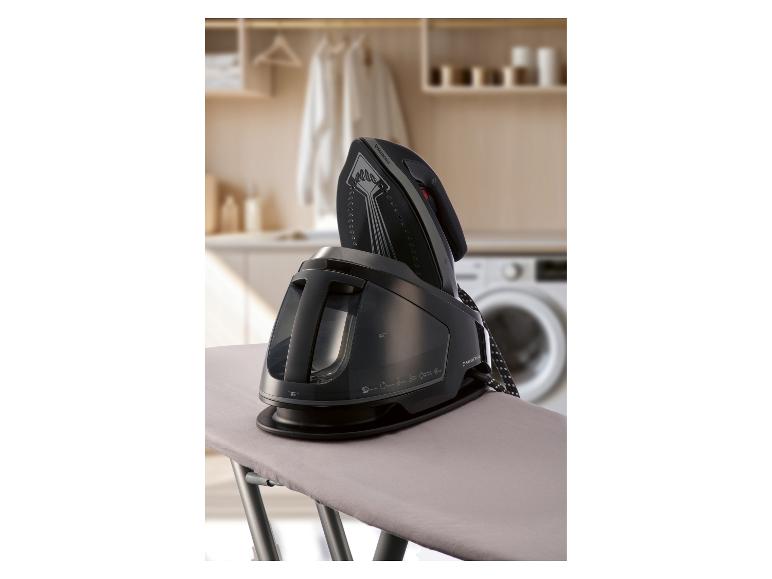 Stoomstrijkijzer op een strijkplank in een wasruimte.