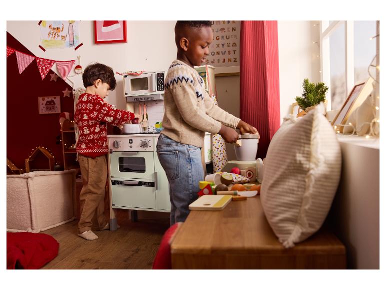 Twee kinderen spelen met een speelgoedkeuken en houten etenswaren.
