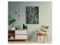 Moderne woonkamer met houten dressoir, plant, ingelijste kunst en rotan stoel.