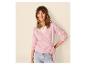 Vrouw in roze wikkelvest en lichte jeans, glimlachend.