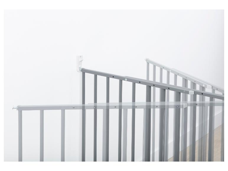 Grijs metalen veiligheid hek voor kinderen, gemonteerd aan de muur.