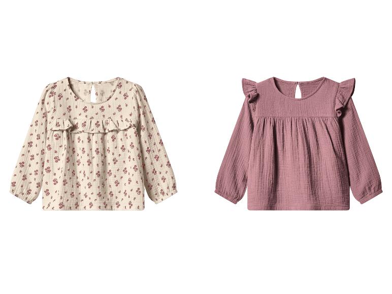 Twee kinderblouses, één beige met bloemenprint en één effen roze, beide met lange mouwen.