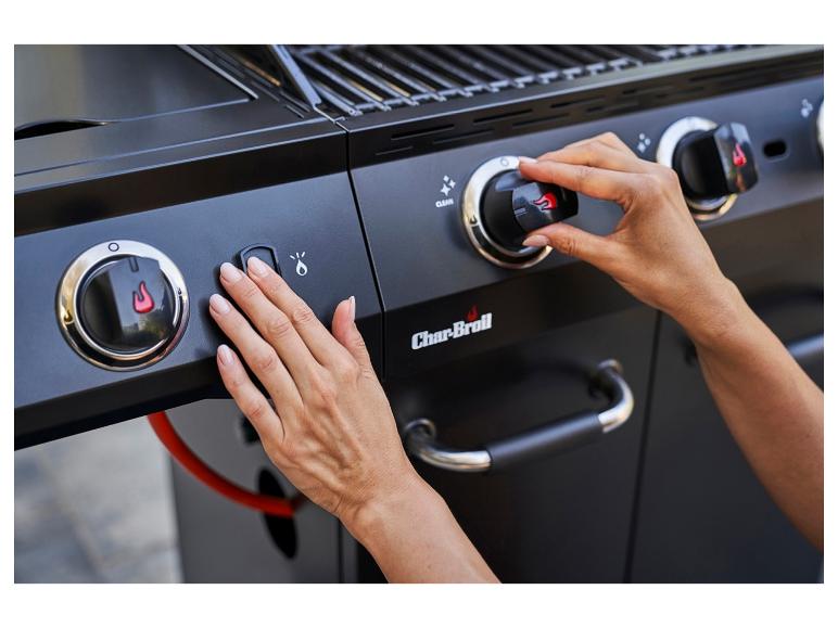 Handen die de knoppen van een zwarte gasbarbecue afstellen.