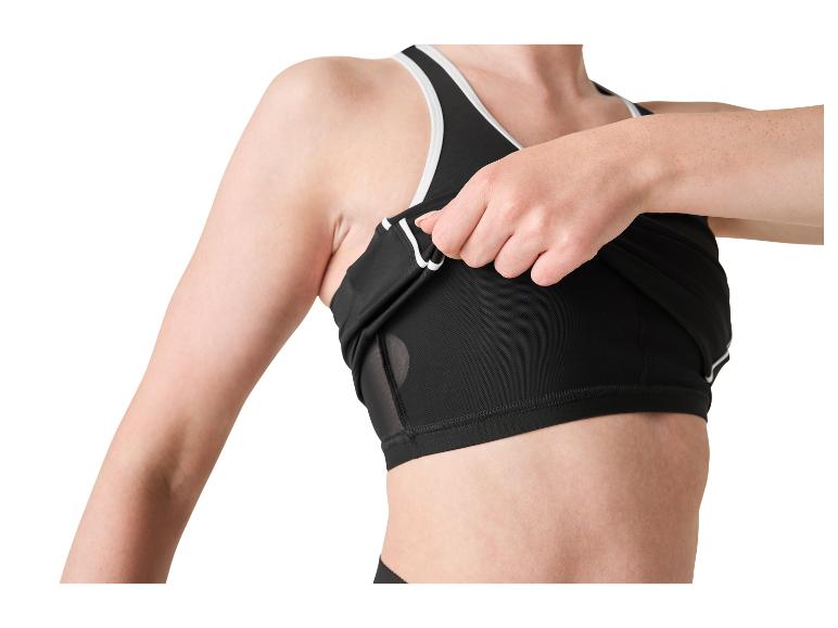 Vrouw tilt de onderkant van een zwarte sporttop met witte details op.