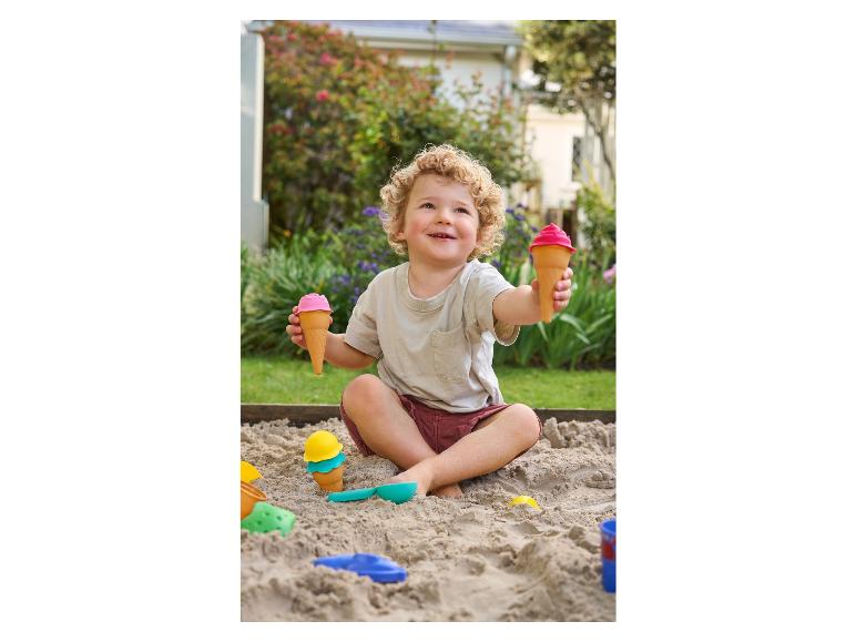 Een jongen speelt in de zandbak met ijsjes-speelgoed.