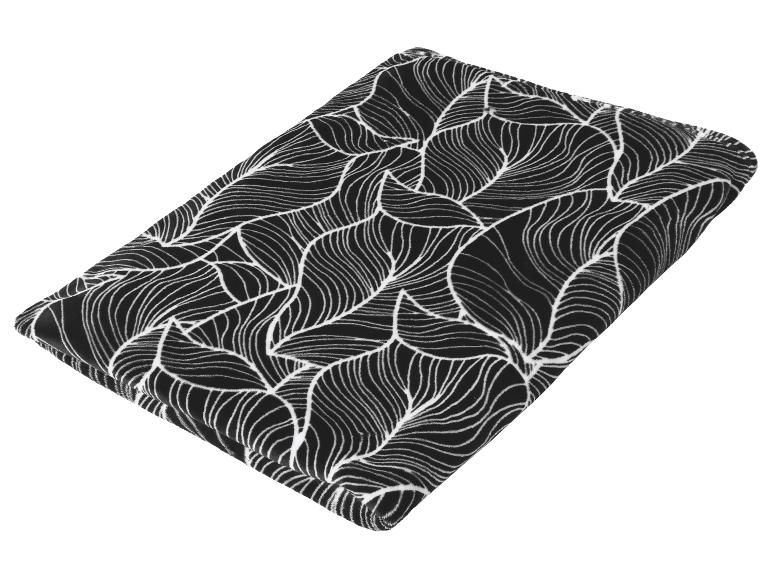 Zwarte fleece deken met wit bladpatroon, opgevouwen.