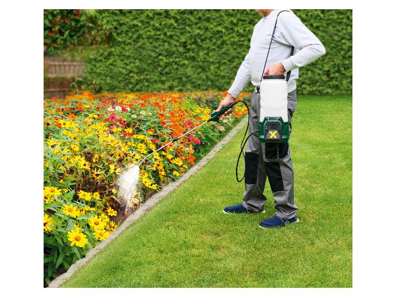 Man besproeit bloembed met handspuit, accuspuit op zijn rug.