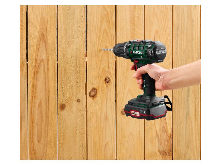 Een hand houdt een Parkside accuboormachine vast, die in een houten hek boort.