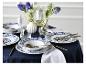 Blauw-wit servies met gouden bestek en bloemen op een gedekte tafel.