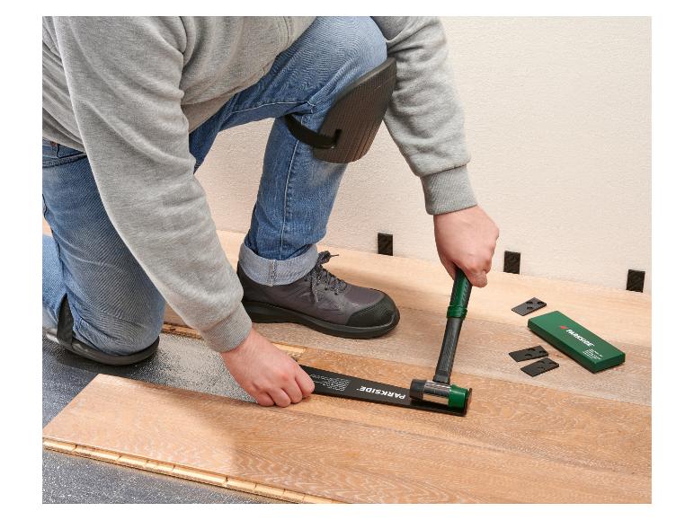 Man installeert laminaatvloer met rubberen hamer en afstandhouders.