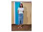 Vrouw in een wit geribbeld T-shirt en een denim midi-rok, blootsvoets staand op zand.