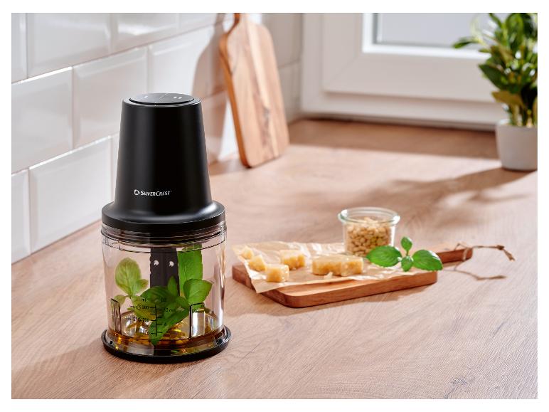 Zwarte Silvercrest hakmolen met basilicum en olie, naast kaas en pijnboompitten.