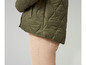 Groene gewatteerde jas en beige broek.