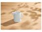 Witte keramische melkkan op een lichte houten tafel met gevlekt zonlicht en schaduwen