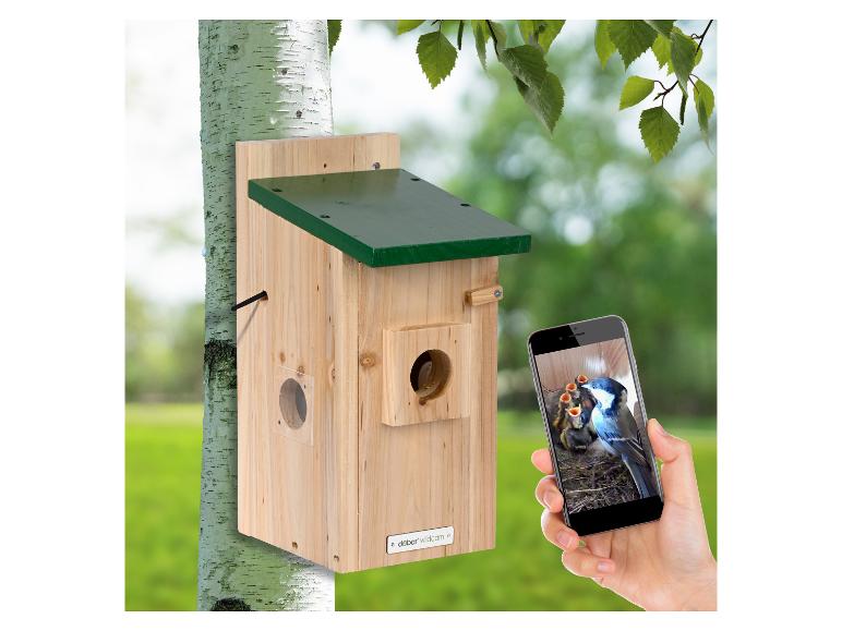 Houten vogelhuisje met groen dak, toont jonge vogels op een smartphone.