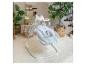 Babyschommel met een patroon zitting in een woonkamer met planten en decoratie.