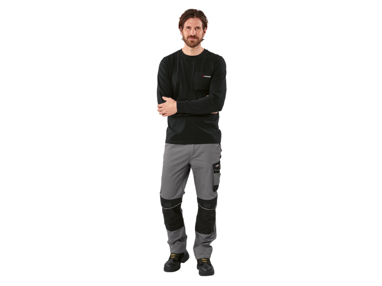 Een man in een zwart shirt met lange mouwen en een grijze werkbroek met kniebeschermers