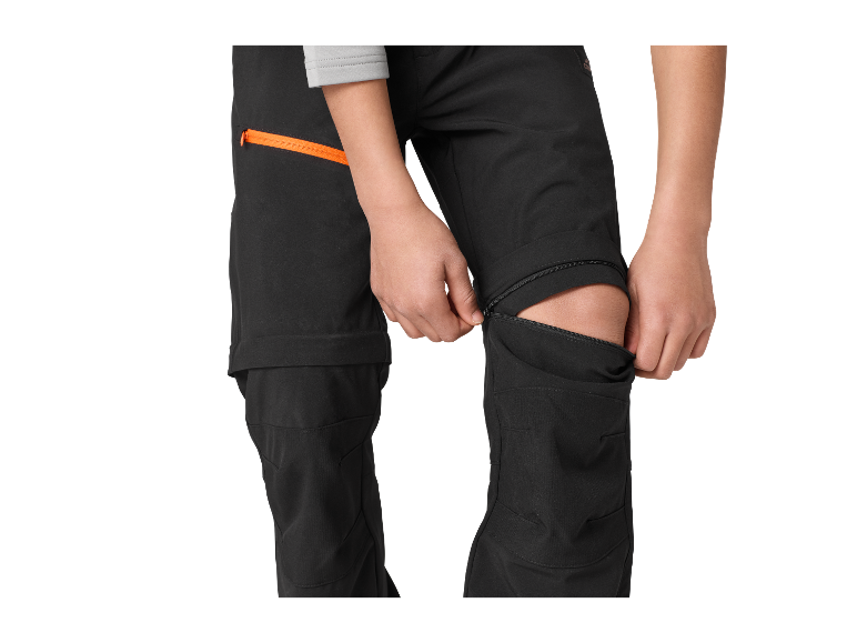 Kind past softshellbroek aan met ritsen bij de knieën.