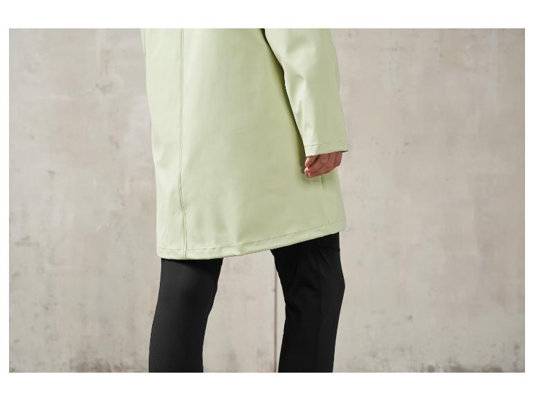 Een lichtgroene regenjas met zwarte leggings.