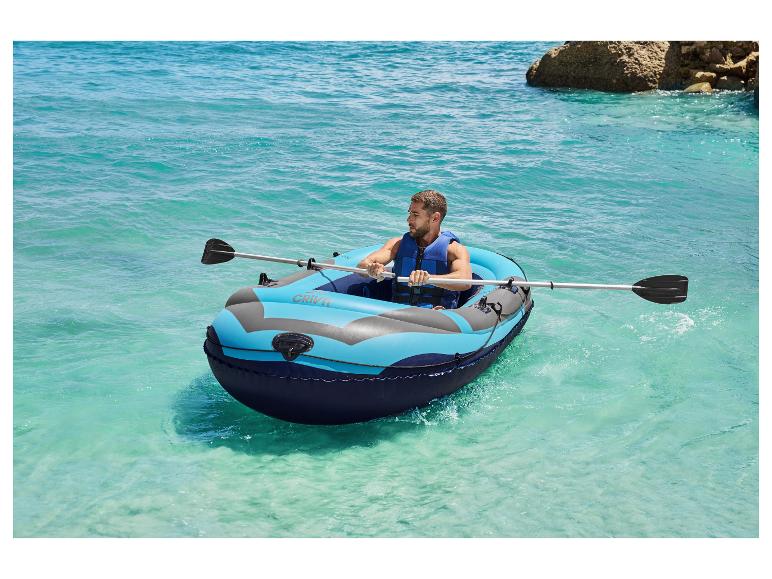 Een man peddelt in een Crivit opblaasboot op een turquoise zee.