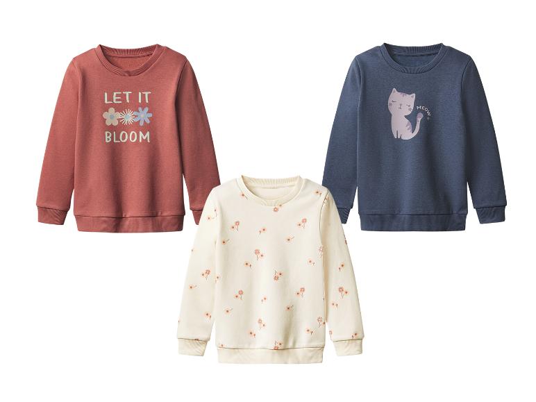 Drie kindertruien met bloemen, een kat en tekstprint.