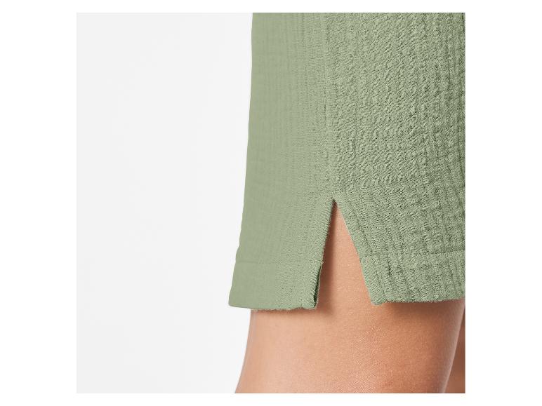 Close-up van een groene, getextureerde stoffen zoom met een kleine split, die een deel van een been onthult.