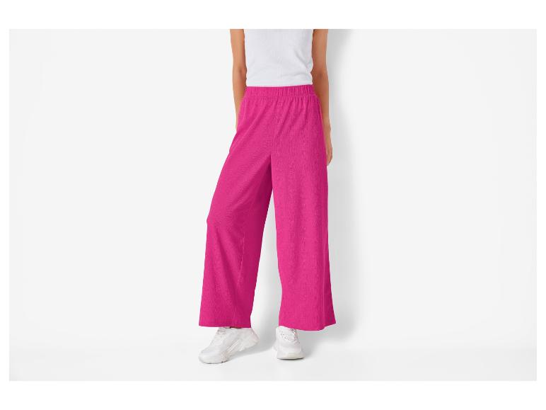 Felle roze wijde broek en witte sneakers.