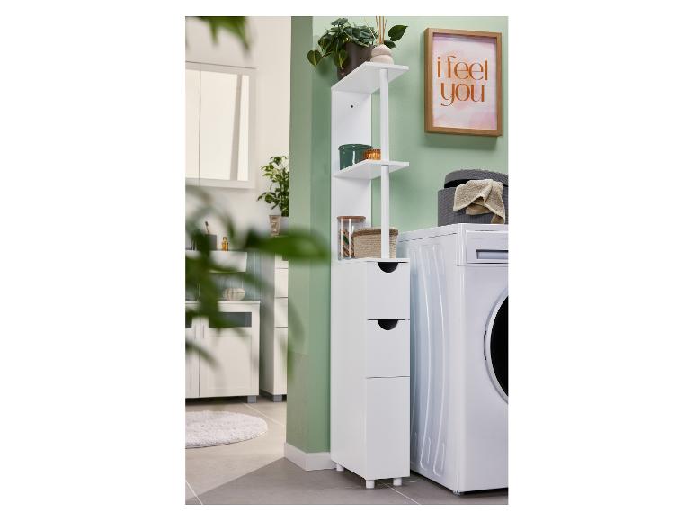 Badkamer met wasmachine, witte kast met lades en planken, en een ingelijste afbeelding.