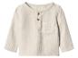 Crèmekleurig kinder shirt met lange mouwen, knopen en zak.