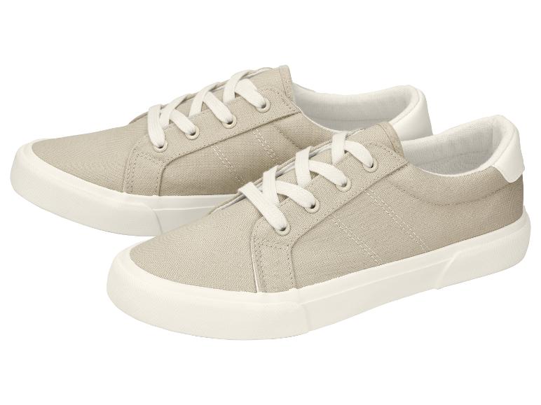 Een paar beige canvas sneakers met witte veters.