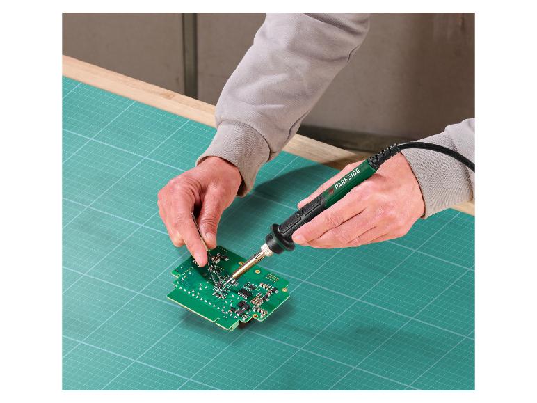 Een persoon gebruikt een Parkside soldeerbout om aan een printplaat te werken.