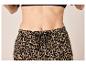 Vrouw in luipaardprint broek met trekkoord tailleband en zwarte beha.