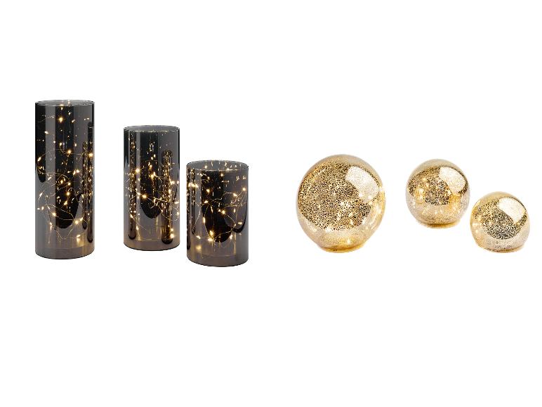 Drie cilindrische vazen met lichtjes en drie gouden decoratieve bollen.