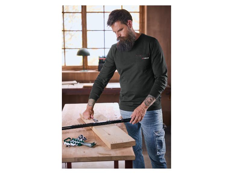 Man met baard in een Parkside shirt met lange mouwen en jeans, werkend aan een stuk hout.