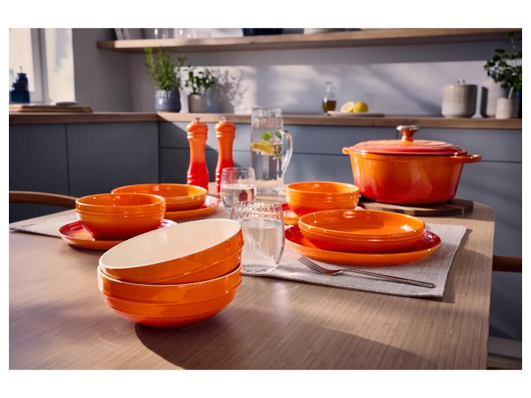 Oranje gietijzeren pan van SILVERCREST® en servies op een gedekte tafel.