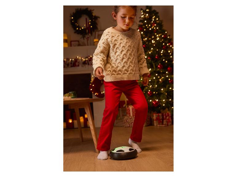 Meisje speelt voetbal met een zweefbal in een kerstsetting.