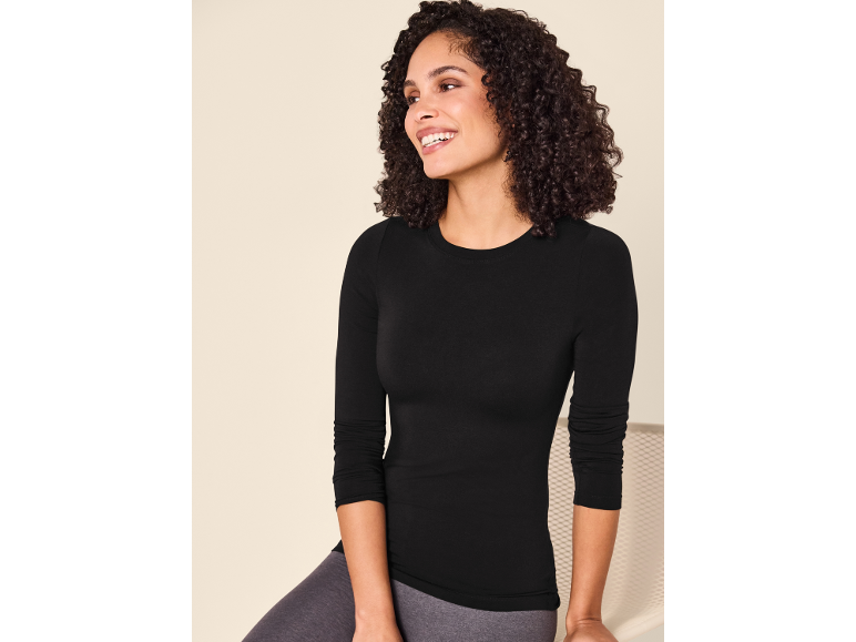Lachende vrouw in een zwart shirt met lange mouwen en grijze legging.
