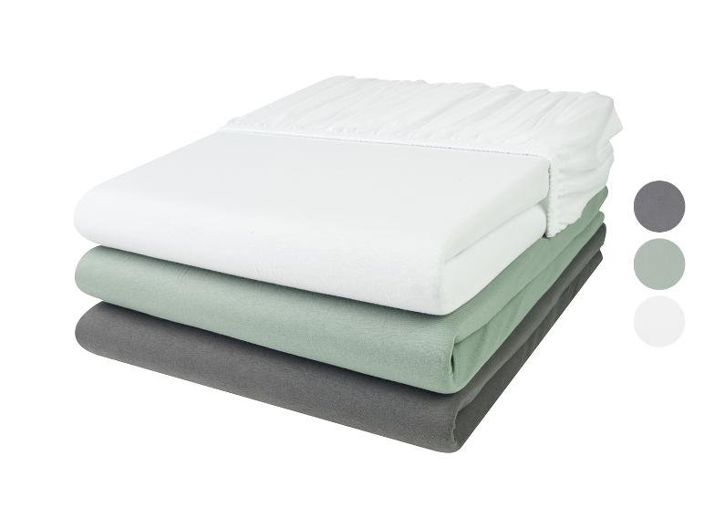 Een witte, groene en grijze hoeslakenset.