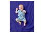 Baby in een blauwe strand-romper, liggend op een blauwe deken.