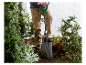 Een tuinier gebruikt een Parksid schop om te planten in een tuin.