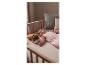 Baby slaapt in wieg in roze slaapzak met oplichtend knuffeldier.