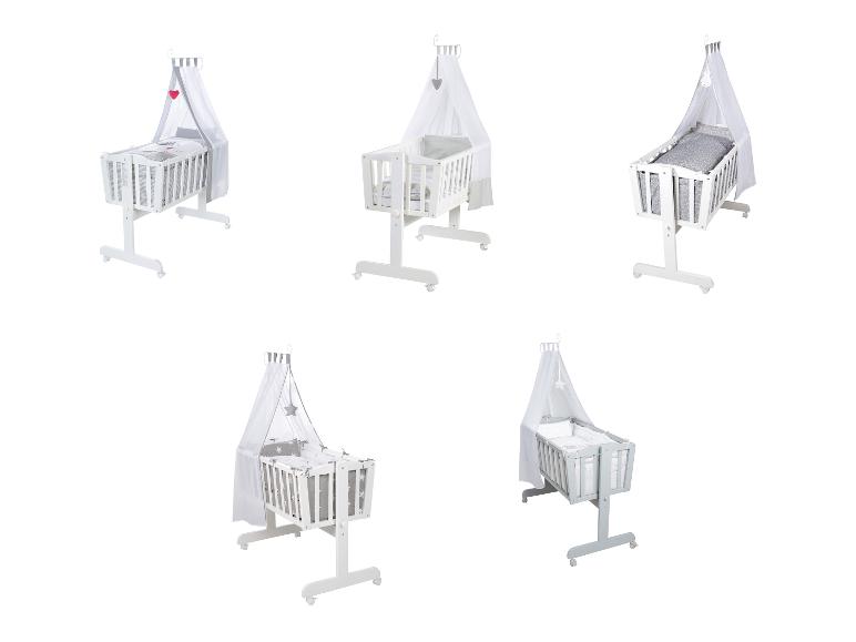 Vijf witte en grijze babybedjes met hemel en diverse beddengoedpatronen.