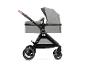 Grijze kinderwagen met reiswieg en bruine handgreep, zijaanzicht.