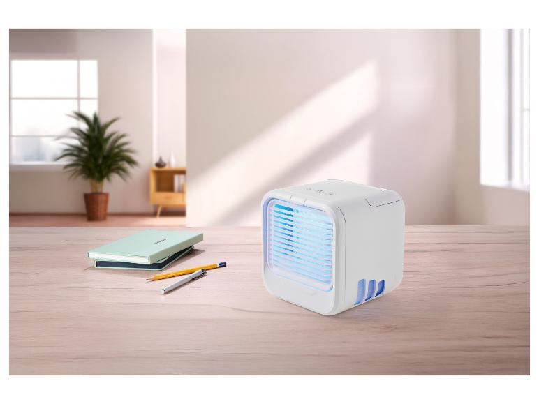 Draagbare luchtkoeler met blauw licht op een houten bureau met notitieboekjes en pennen