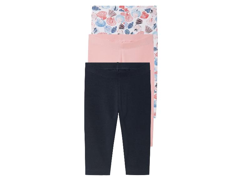 Drie leggings voor kinderen: één met schelpjesprint, één roze en één donkerblauw.