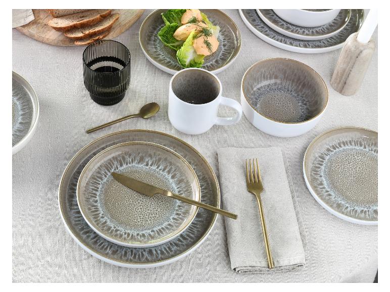 Tafel gedekt met aardewerk borden, kommen en mokken, gouden bestek en brood.
