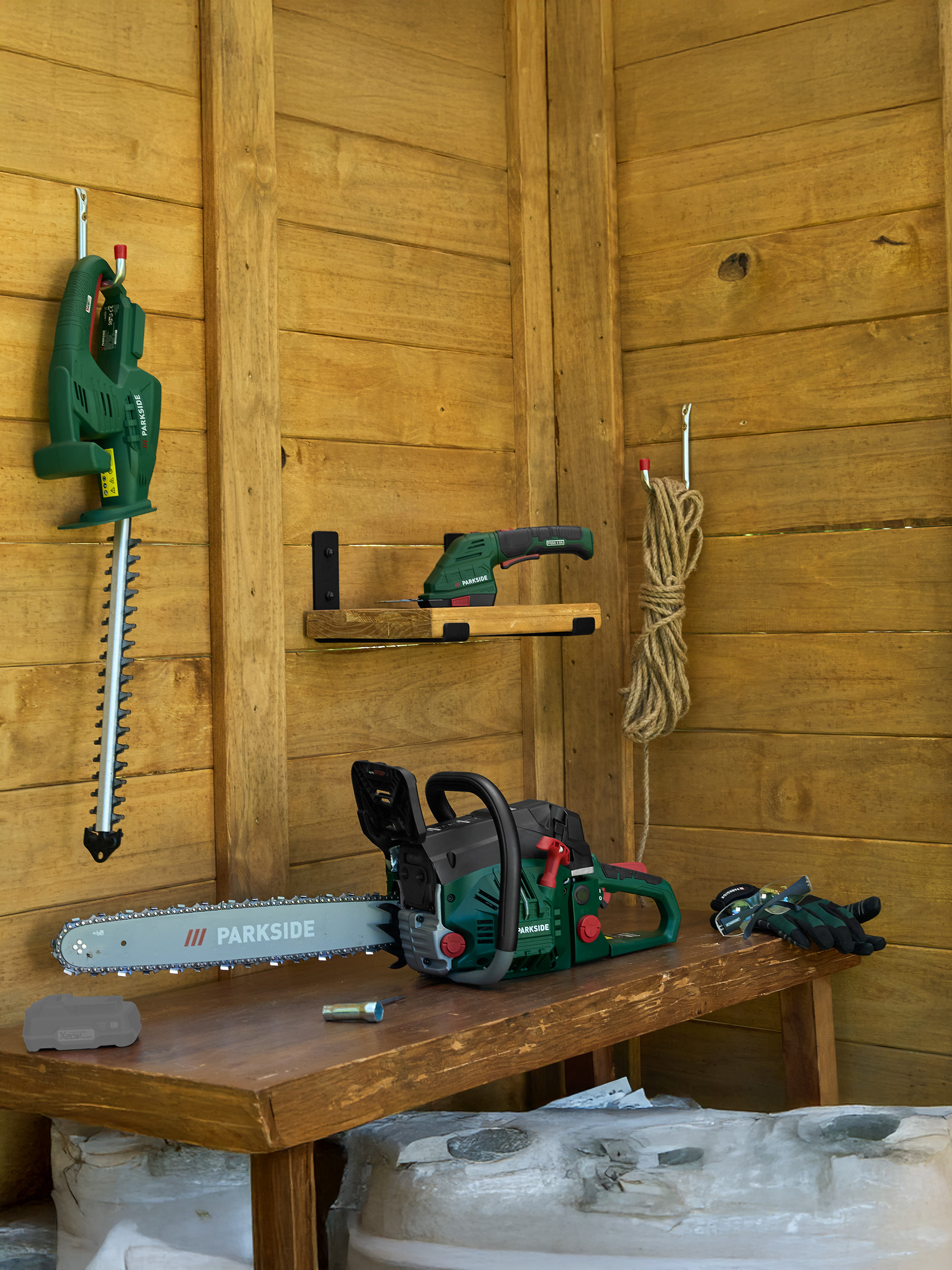Kettingzaag, heggenschaar en tuinschaar in een houten schuur met tuingereedschap.