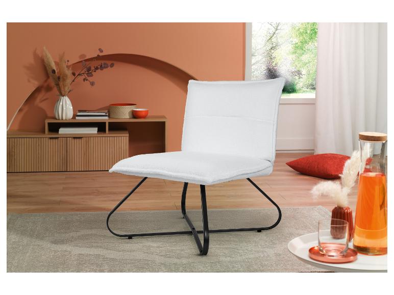 Een zachte witte fauteuil met een zwart metalen frame in een moderne woonkamer.