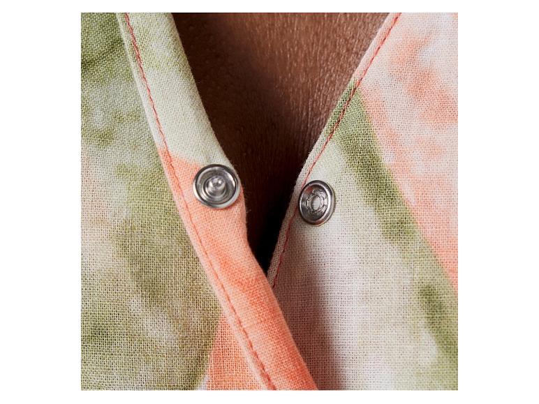 Detail van een jurk met drukknopen, lichte stof, oranje en groene tie-dye print.