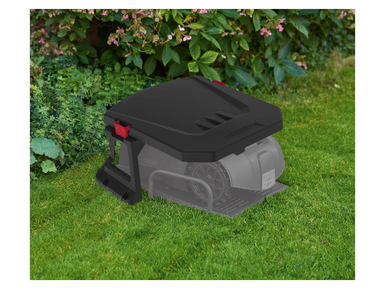 Robotmaaier met laadstation op groen gras voor struiken.